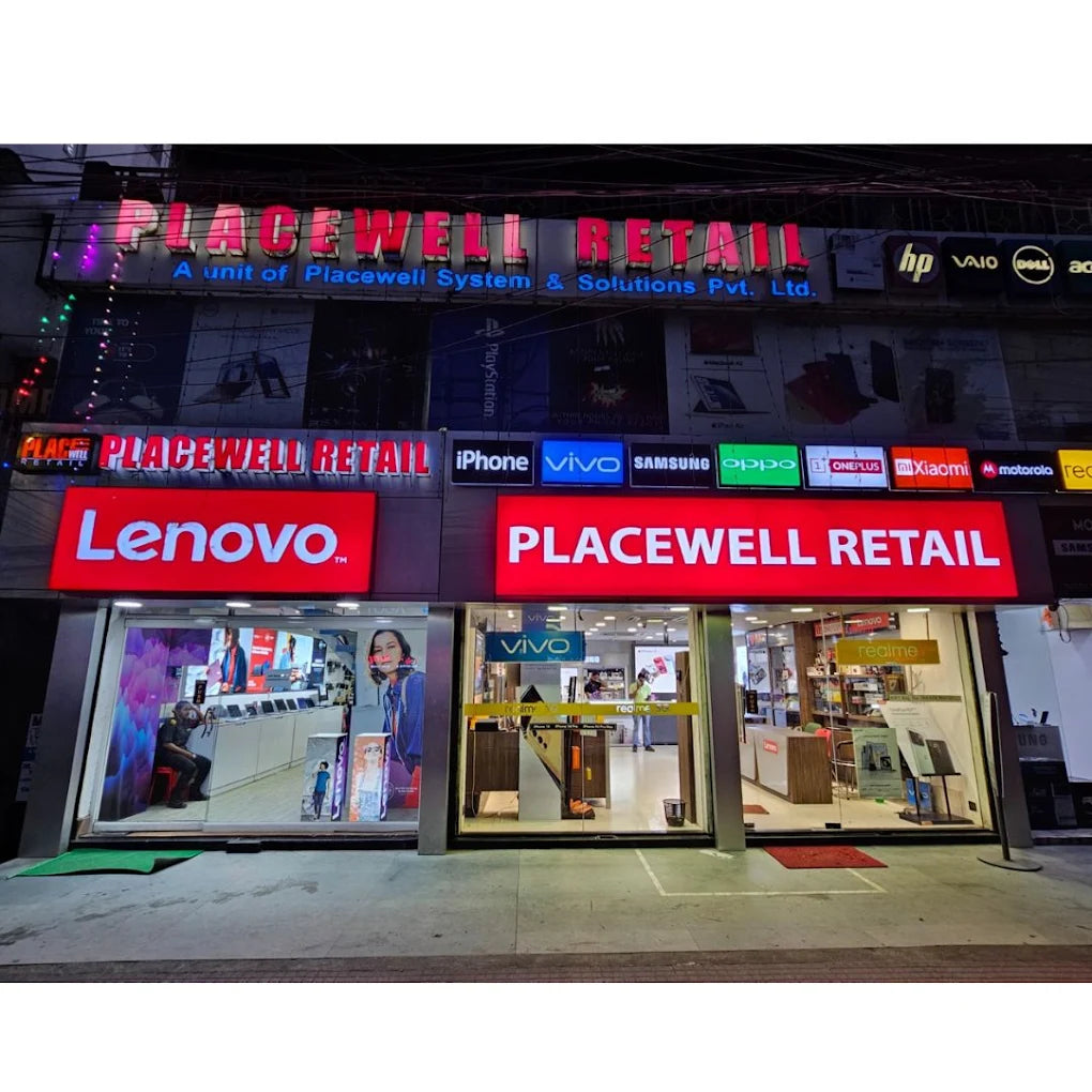 Placewell Retail store front at night, showcasing Lenovo, iPhone, Samsung, and other electronics brands